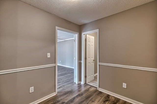 unfurnished room with a textured ceiling, wood finished floors, and baseboards