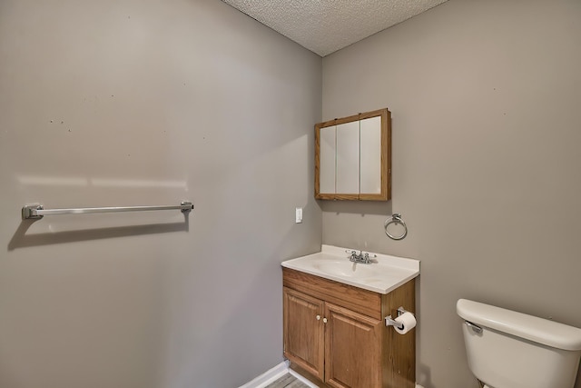 half bathroom featuring a textured ceiling, toilet, and vanity