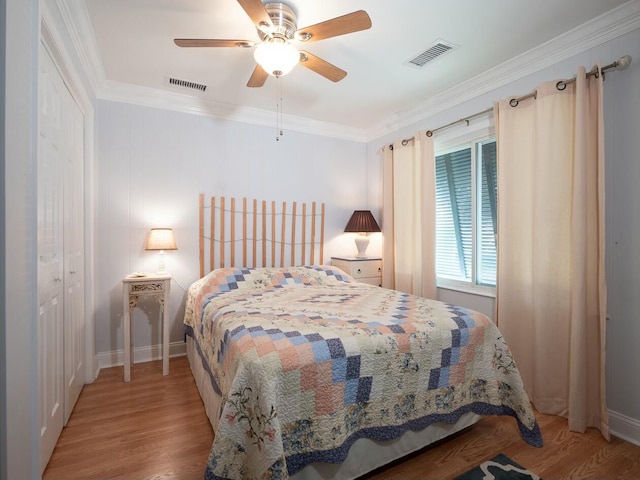 bedroom featuring ceiling fan, light hardwood / wood-style floors, crown molding, and a closet