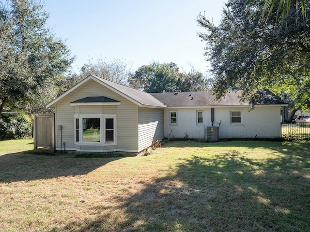 rear view of house featuring cooling unit and a yard