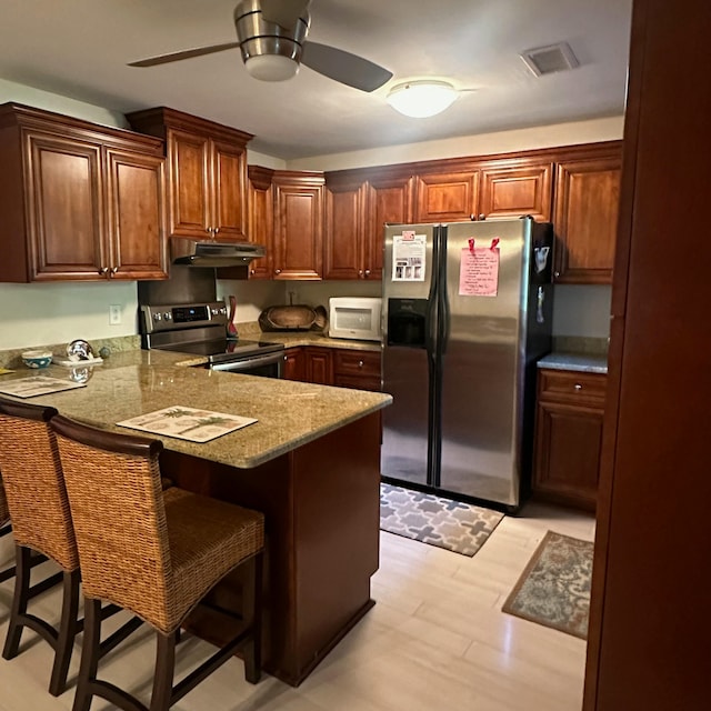 kitchen featuring kitchen peninsula, a breakfast bar, stainless steel appliances, and light wood-type flooring