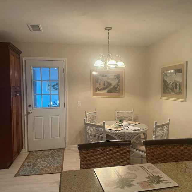 dining space with light wood-type flooring and an inviting chandelier