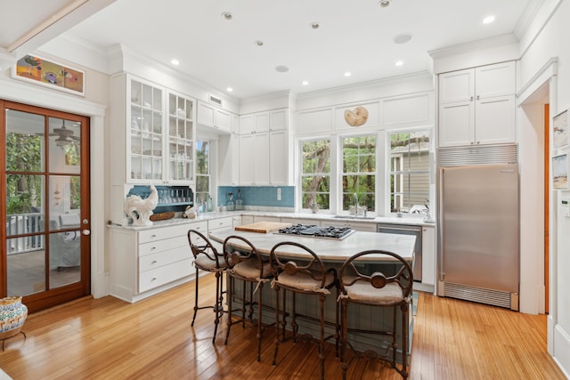 1612 John Fenwick Ln, Johns Island, SC 29455 - kitchen featuring appliances with stainless steel finishes, crown molding, light countertops, a breakfast bar, and white cabinets