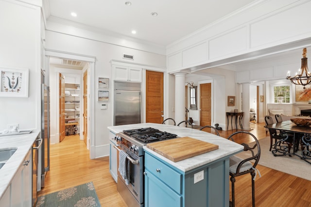 1612 John Fenwick Ln, Johns Island, SC 29455 - kitchen with high end appliances, blue cabinets, ornate columns, a breakfast bar, and ornamental molding