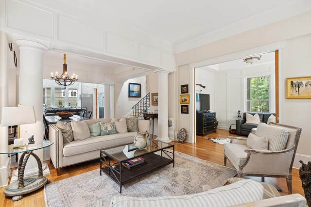 1612 John Fenwick Ln, Johns Island, SC 29455 - living room featuring decorative columns, a chandelier, wood finished floors, crown molding, and stairway