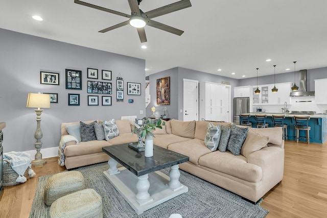 living room featuring ceiling fan, light hardwood / wood-style flooring, and sink