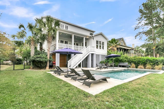 back of house featuring a lawn, ceiling fan, a patio area, and a fenced in pool