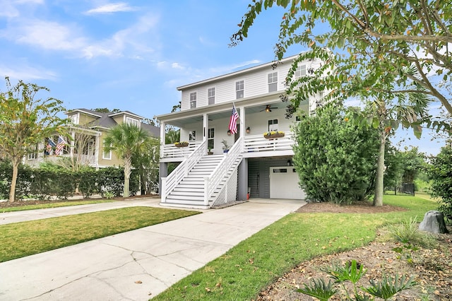 raised beach house featuring a garage, covered porch, and a front yard