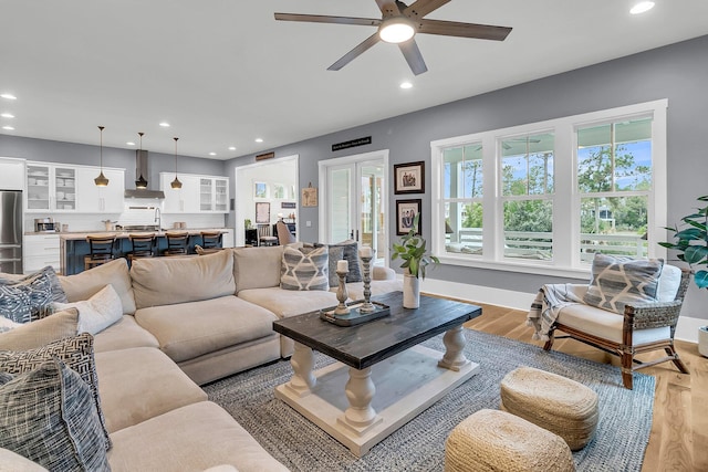 living room featuring ceiling fan, light hardwood / wood-style flooring, french doors, and sink