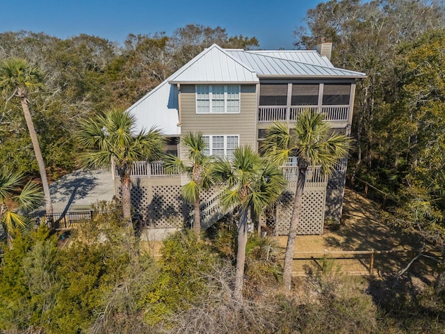 view of home's exterior with metal roof, fence, a sunroom, a standing seam roof, and a chimney