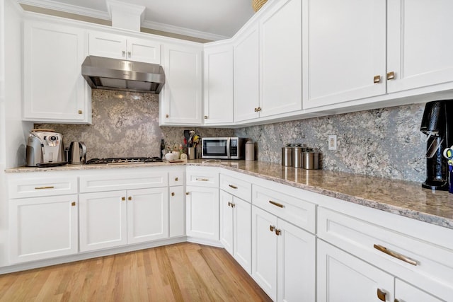 kitchen featuring tasteful backsplash, appliances with stainless steel finishes, light wood-style floors, white cabinets, and under cabinet range hood