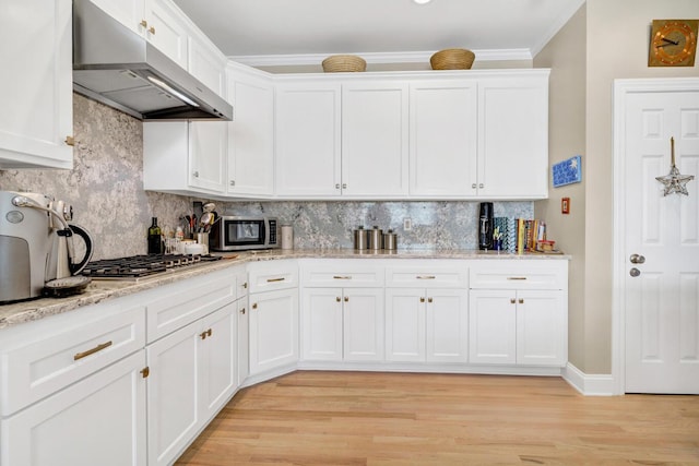 kitchen with white cabinets, appliances with stainless steel finishes, ornamental molding, under cabinet range hood, and backsplash