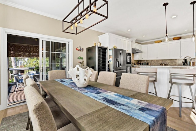 dining room with light wood-style floors, crown molding, and recessed lighting