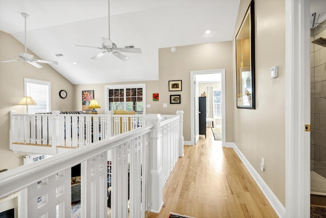 hallway with lofted ceiling, recessed lighting, visible vents, light wood-style flooring, and baseboards