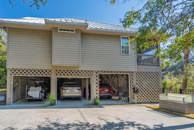 view of home's exterior featuring driveway, a standing seam roof, metal roof, and a carport