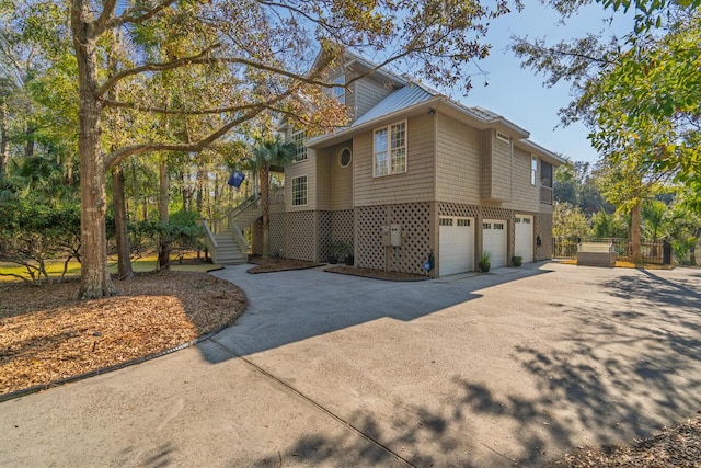 view of side of home with a garage, driveway, and stairs