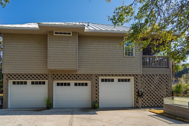 view of side of property featuring a garage, a standing seam roof, metal roof, and concrete driveway