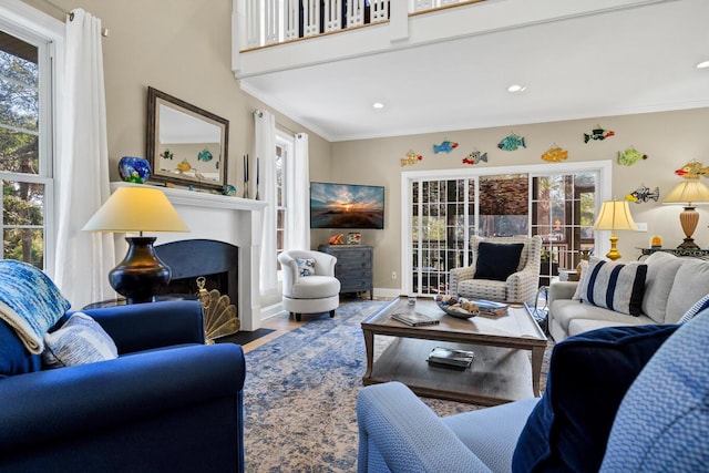 living area with a fireplace with flush hearth, crown molding, plenty of natural light, and wood finished floors