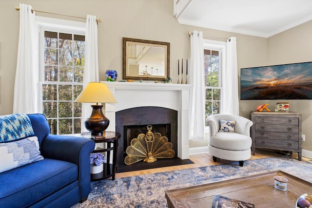 living room featuring wood finished floors, ornamental molding, a fireplace with flush hearth, and baseboards