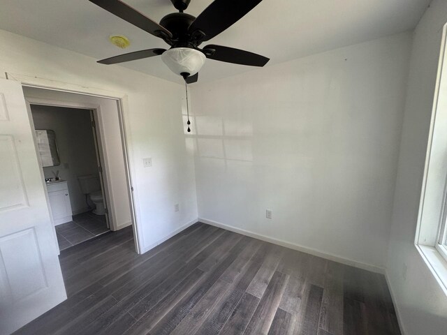 unfurnished room featuring dark wood-style floors, a ceiling fan, and baseboards