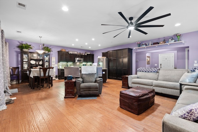 living area featuring light wood finished floors, a ceiling fan, visible vents, and recessed lighting