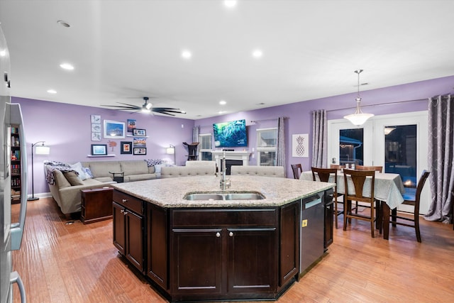 kitchen featuring dishwashing machine, light wood finished floors, a sink, and dark brown cabinets