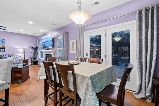 dining space with light wood-style floors, a fireplace, visible vents, and recessed lighting