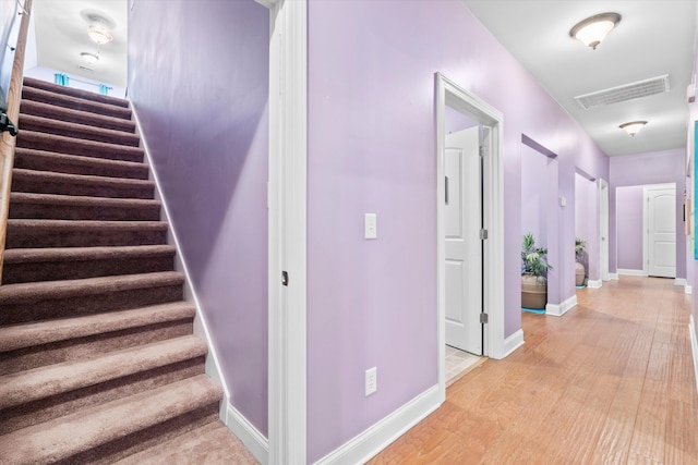 stairway with visible vents, baseboards, and wood finished floors