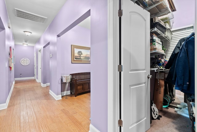 corridor featuring light wood finished floors, visible vents, and baseboards