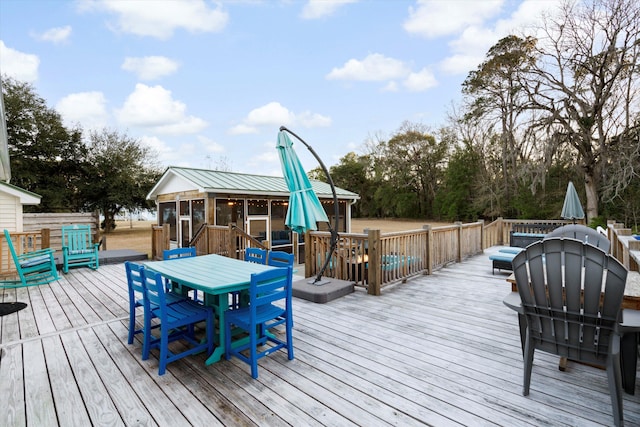 deck with a sunroom and outdoor dining area