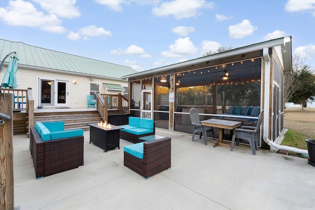 view of patio / terrace featuring a deck, an outdoor living space with a fire pit, and a sunroom