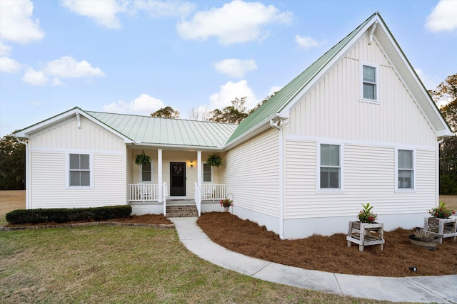 view of front facade with metal roof, a front lawn, a porch, and board and batten siding