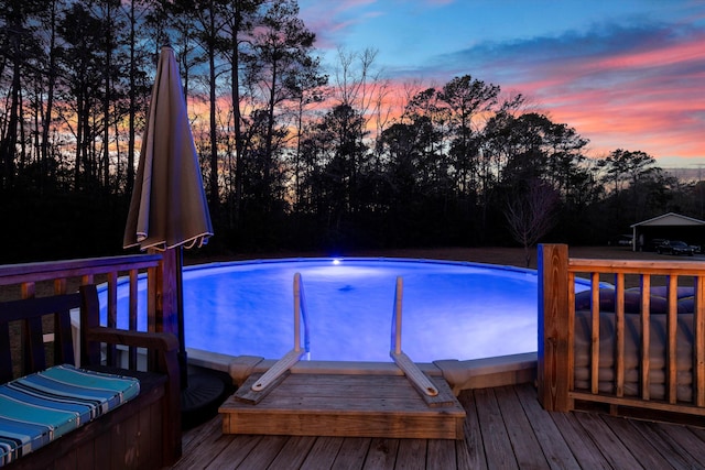 pool at dusk with a wooden deck and an outdoor pool