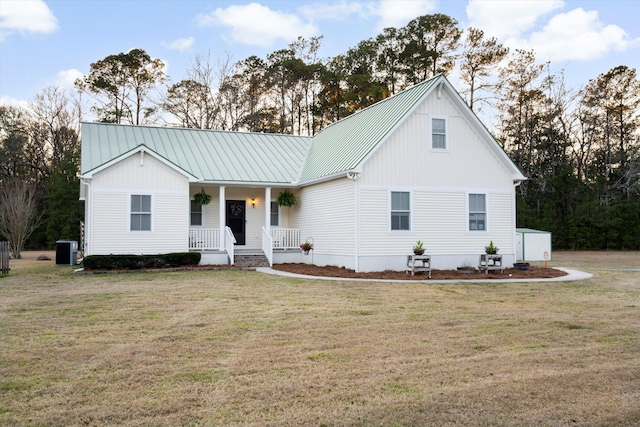 view of front of home featuring central air condition unit, covered porch, metal roof, and a front yard