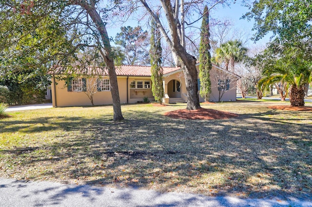 ranch-style home featuring stucco siding, a tile roof, and a front yard