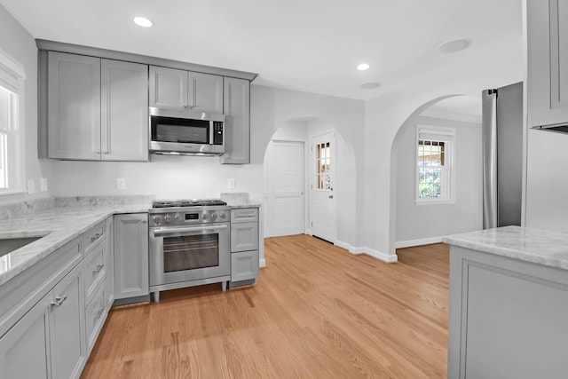 kitchen featuring light stone counters, light wood-style flooring, recessed lighting, gray cabinetry, and stainless steel appliances