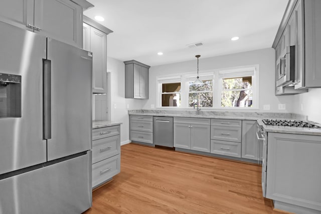 kitchen featuring recessed lighting, gray cabinetry, stainless steel appliances, a sink, and light wood-style floors