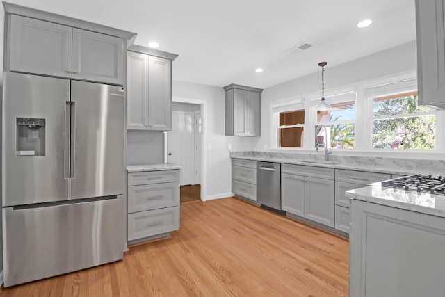 kitchen with gray cabinetry, a sink, visible vents, appliances with stainless steel finishes, and light wood-type flooring