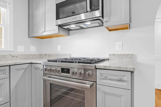 kitchen featuring appliances with stainless steel finishes, gray cabinets, and light stone counters