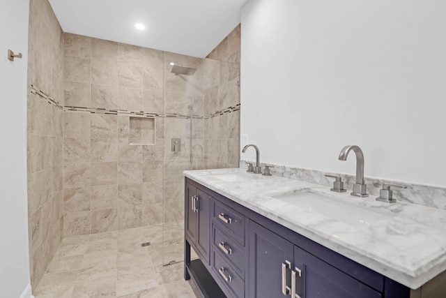 full bathroom with double vanity, a walk in shower, and a sink