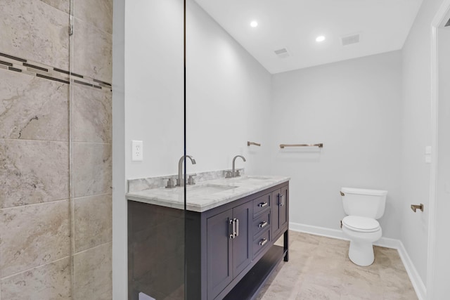 bathroom featuring double vanity, a sink, toilet, and baseboards