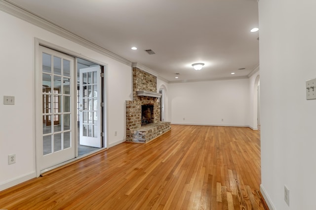 unfurnished living room with light wood finished floors, ornamental molding, and a brick fireplace