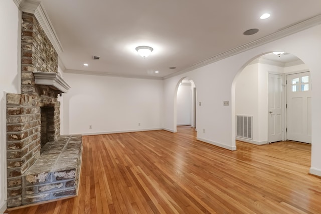 unfurnished living room with arched walkways, a brick fireplace, visible vents, and light wood-style floors