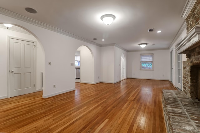 unfurnished living room with baseboards, visible vents, ornamental molding, light wood-style floors, and a fireplace