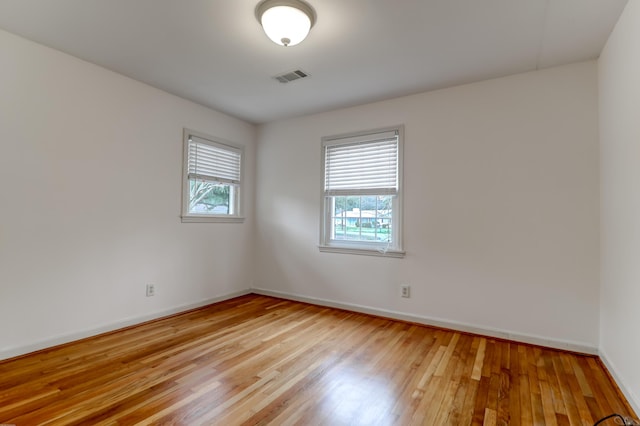 unfurnished room featuring baseboards, visible vents, and light wood-style floors