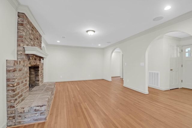 unfurnished living room with crown molding, visible vents, a brick fireplace, light wood-type flooring, and baseboards