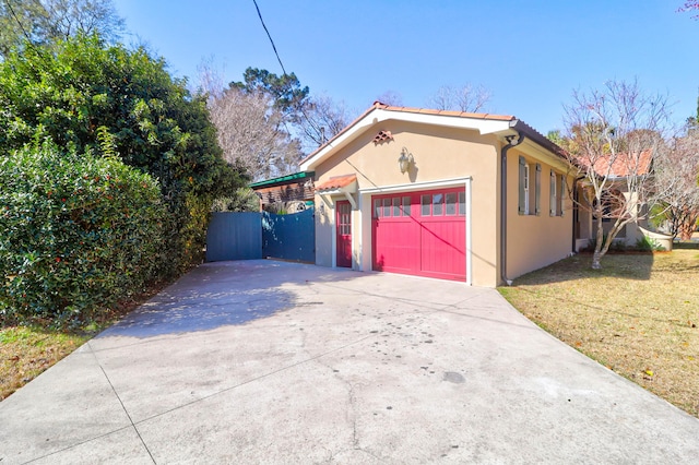 view of home's exterior featuring a garage, a lawn, concrete driveway, fence, and stucco siding