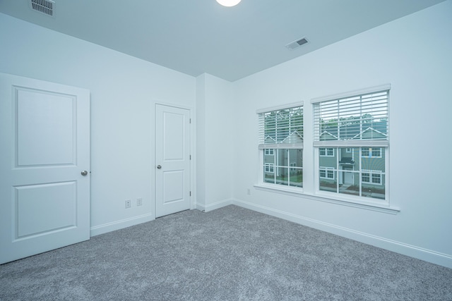 carpeted spare room with visible vents and baseboards