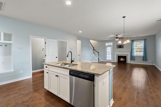 kitchen featuring light stone countertops, white cabinets, a fireplace, sink, and stainless steel dishwasher