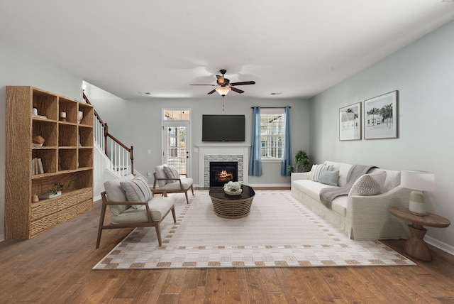 living room with ceiling fan, hardwood / wood-style floors, and a stone fireplace